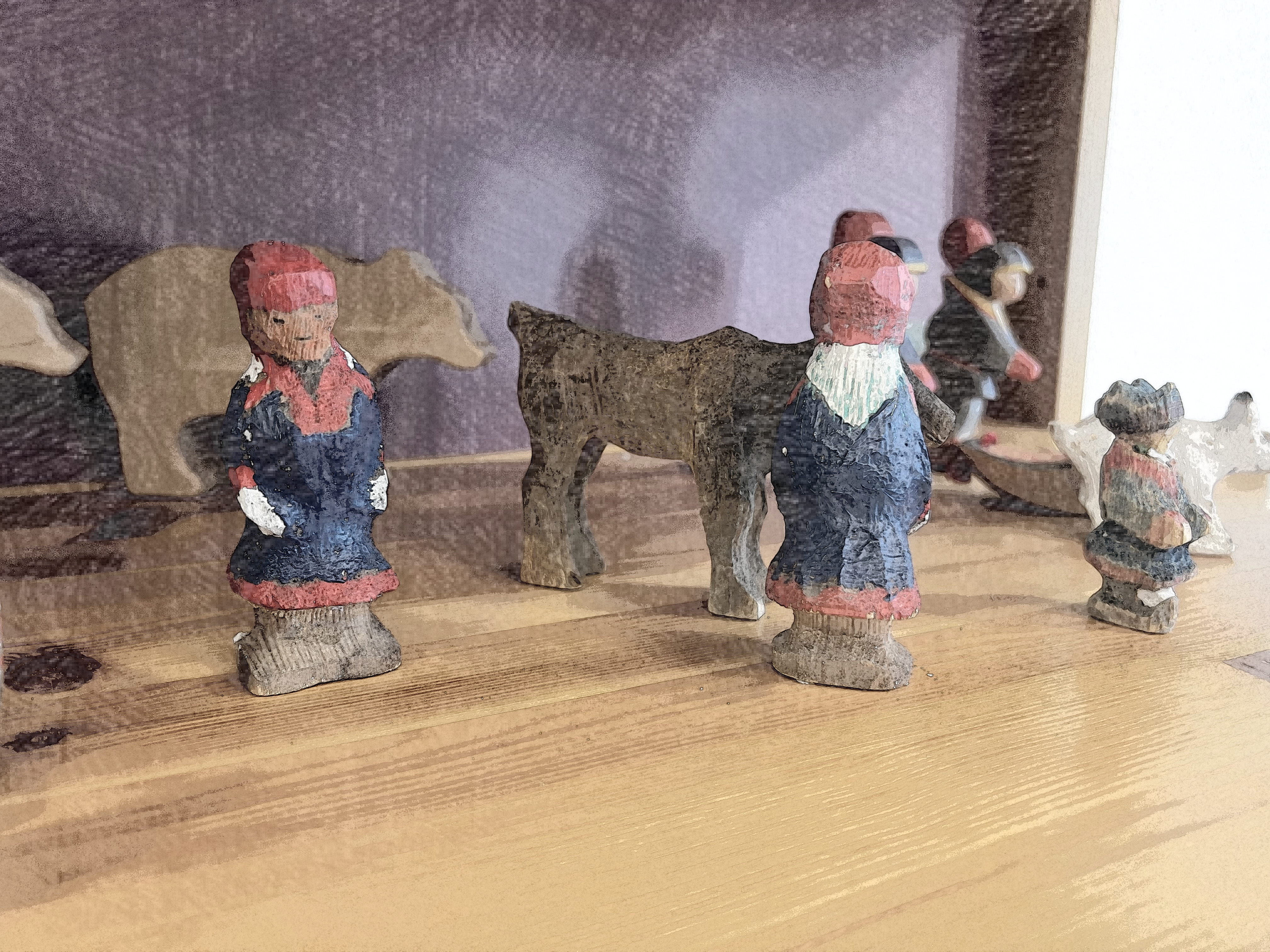 Kuvassa on saamelaislapsen leluja, puisia ihmis- ja eläinhahmoja. Kuva otettu SANKS Norjan Karasjoen yksikön lasten leikkiterapiahuoneesta. Kuva on muokattu piirrosmaiseksi.