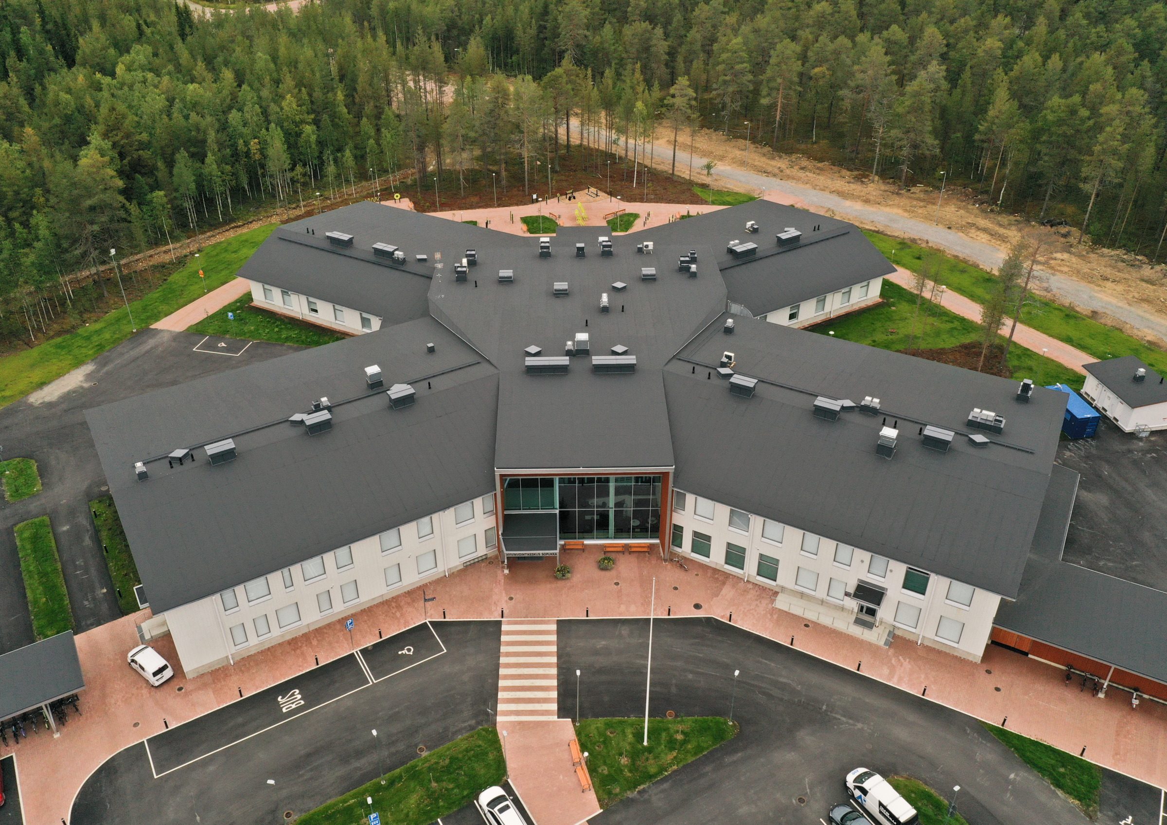Drone-kuva Sodankylän hyvinvointikeskus Sopukasta. Rakennuksessa erottuu suuresta aulasta lähtevät neljä siipeä X-muodossa.
